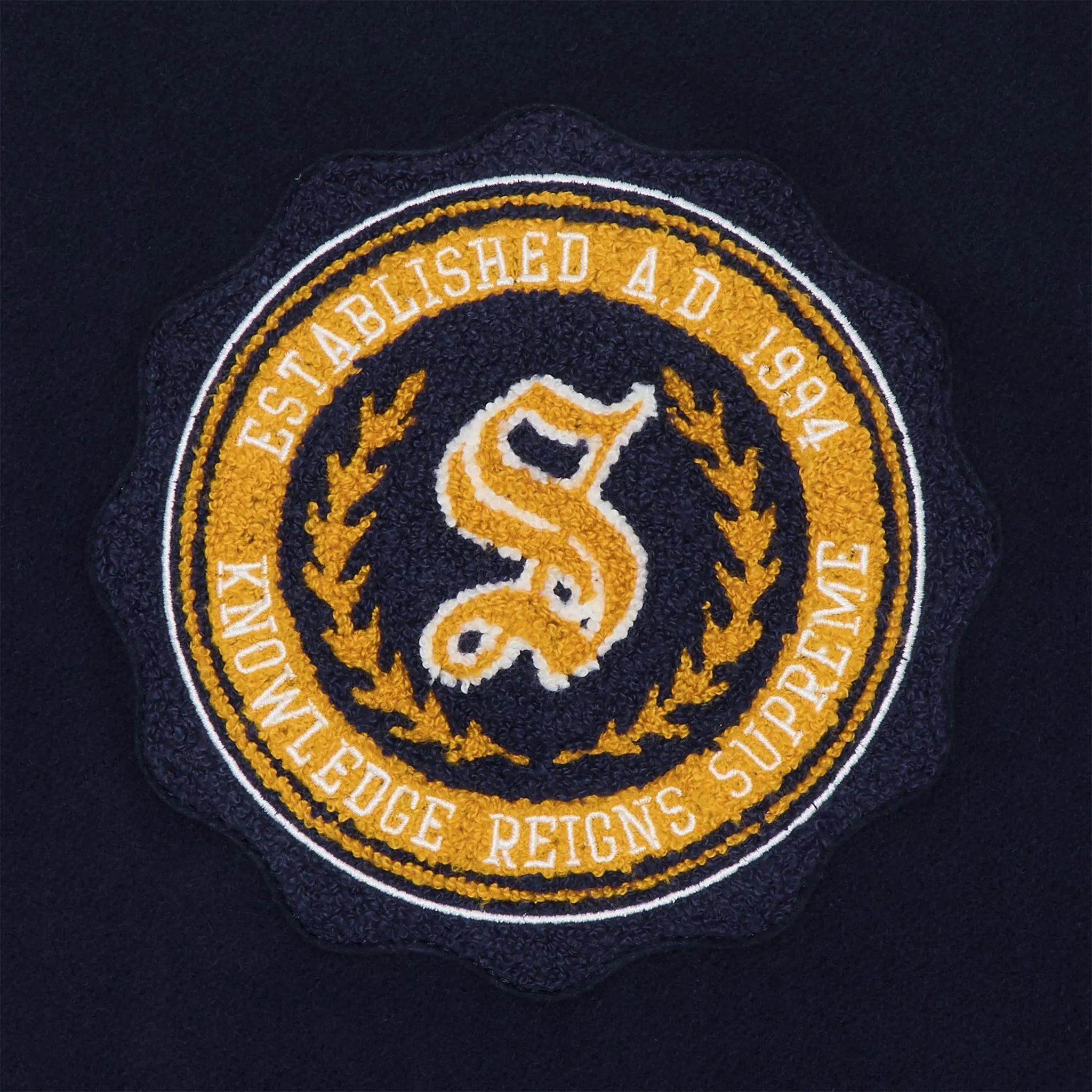 Logo view of Supreme Veritas Varsity Jacket Navy FW24J44 NAVY 